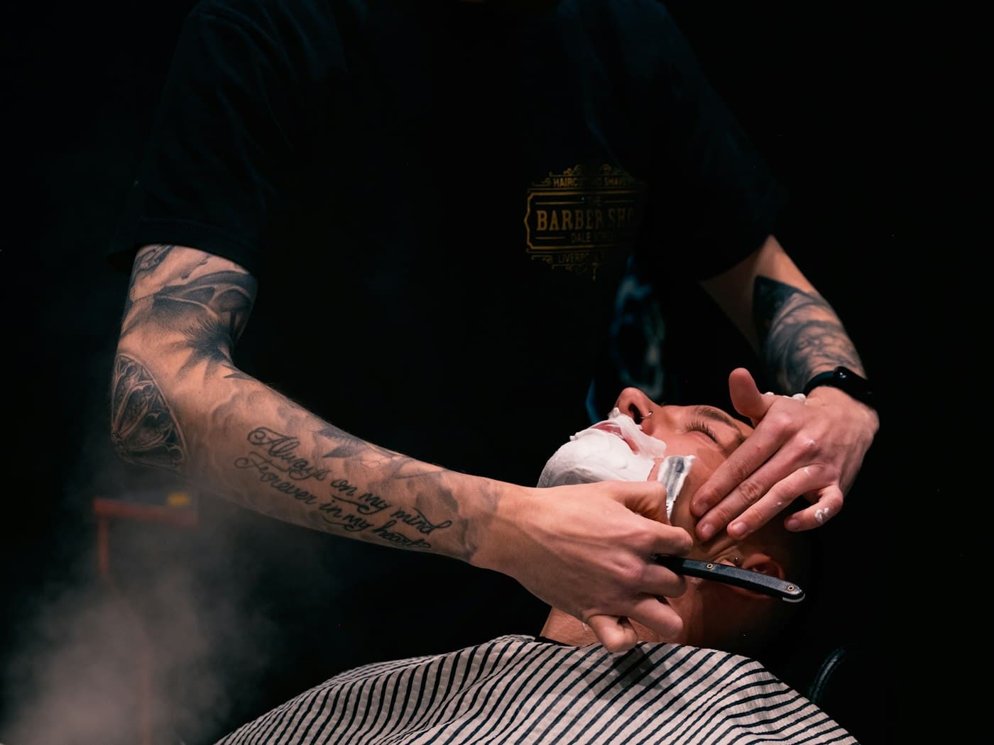 Rasur mit dem Messer im Dampf des heißen Tuchs